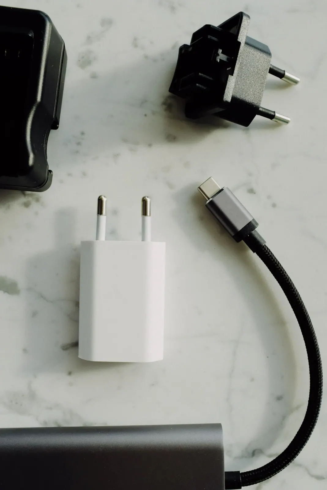 شواحن ومحوّلات كهربائية وكابل USB على سطح أبيض — بطاريات ووصلات USB