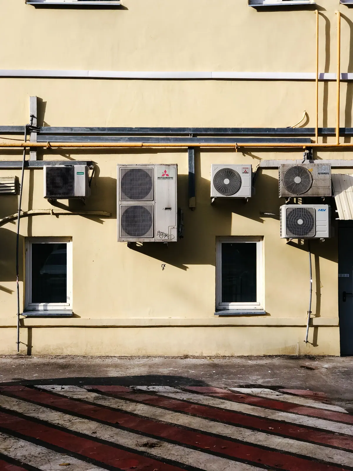 صف من وحدات التكييف الخارجية ومواسيرها على واجهة مبنى — التكييفات الموفرة للطاقة