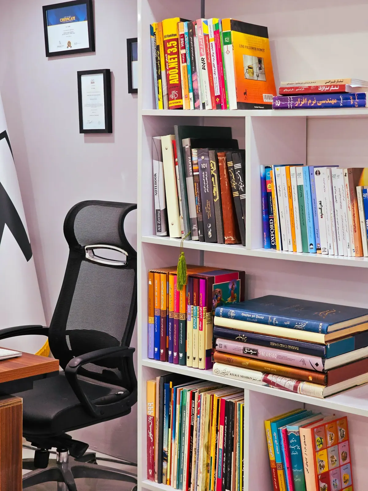 رف كتب ملون بجوار كرسي مكتب دوّار — أرشفة الملفات في المؤسسات